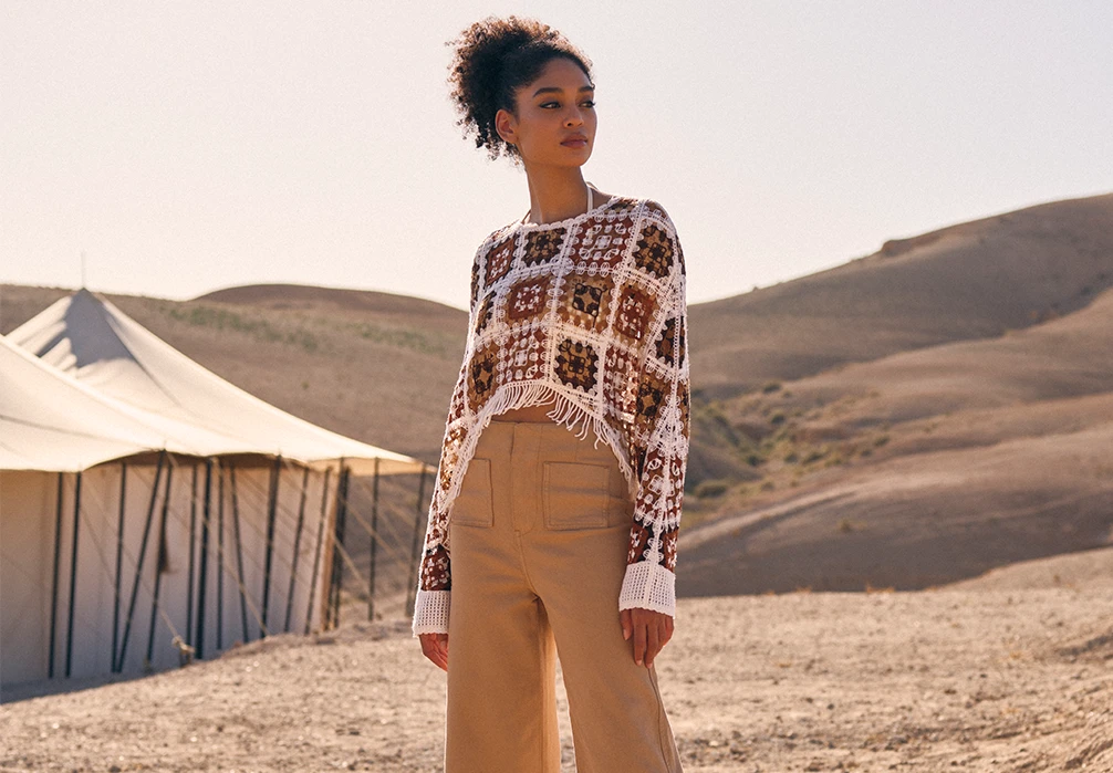 A girl standing in cotton crochet top. Text on image: Tap into this season's crochet trend with colourful tops, dresses and accessories.